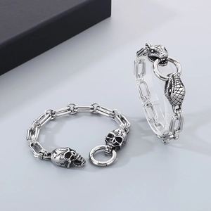 Detail of punk stainless steel bracelets with skull and snake head charms on O-chains