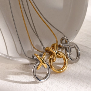 Three heart contrast XO pendant necklaces in gold and silver on a white ceramic bowl