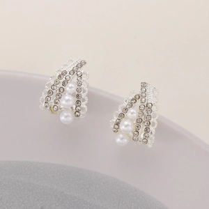 Detailed view of silver C-shape earrings with white pearls and sparkling rhinestones