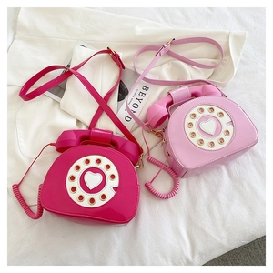 Detail of creative vintage telephone-shaped crossbody bags in glossy pink patent leather