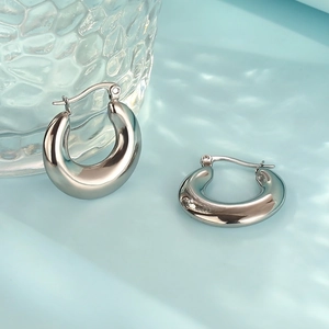 Macro shot of silver oval stainless steel hoop earring on a blue watery background