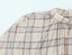 Close-up of beige plaid top with stand collar button detail and seersucker texture