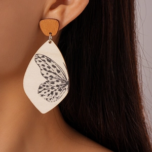 Close-up of wood teardrop earring with butterfly wing print and silver needle pin