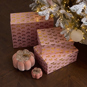 Pink Christmas gift box set with gold bow pattern and festive holiday decorations
