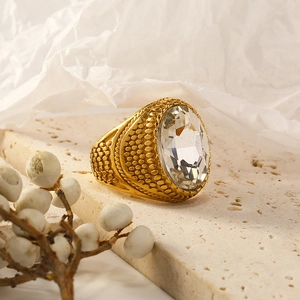 Detailed macro view of a vintage gold ring with large oval clear crystal on travertine stone