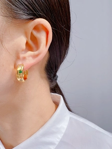 Close-up of gold hoop earrings featuring colorful zircon stones and star details on model