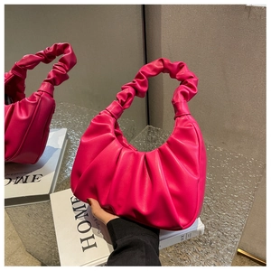 Detail shot of the rose red pleated underarm bag featuring a textured knotted handle design