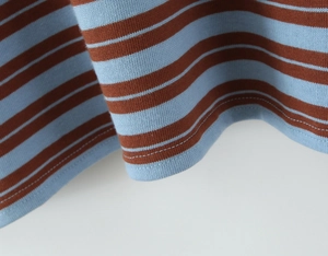 Detailed close-up of the double-stitched hem on the blue and brown striped polo shirt