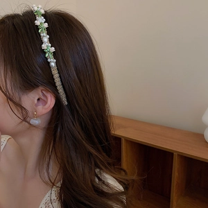 Detail of cream fabric bow headband with pearl lily of the valley and matching earrings