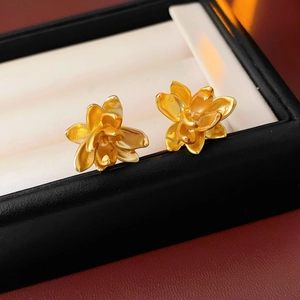 Detailweergave van gouden lotusoorbellen met gelaagde bloembladen op een sieradendoos