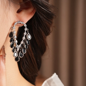 Macro shot of silver tassel earrings with black teardrop crystals and sparkling diamonds