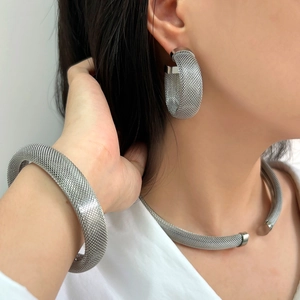 Mesh texture silver stainless steel jewelry set including collar necklace and earrings on model