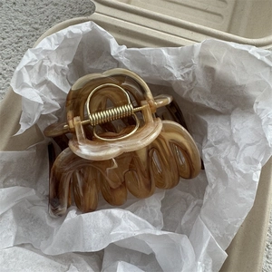 Detailed view of large brown marble pattern resin hair claw clip with metal spring