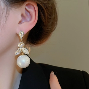 Close-up of pearl drop earrings with tassel crystal accents on a female model