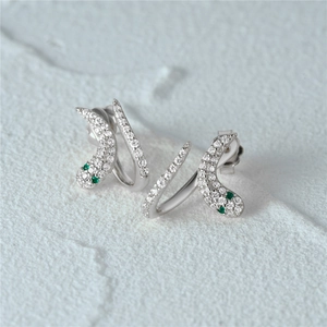 Macro shot of 925 sterling silver snake earrings with white zircons and green eyes