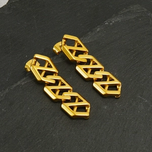 Modern gold stainless steel Z-shape chain earrings on a textured dark rock background