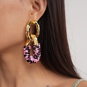 Macro view of gold metal hoops with pink leopard print fabric wrap on model's ear