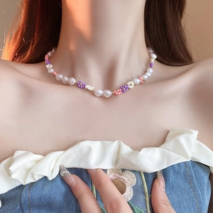 Close-up of beaded flower necklace with faux pearls and pastel beads on neck