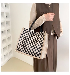 Detail of checkered tote bag showing beige and black linen texture with durable black handles