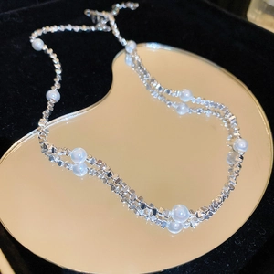 Detailansicht der silbernen Choker-Halskette mit weißen Perlen auf Goldspiegel