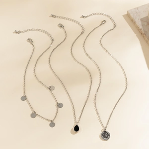 Detailed view of silver layered chain necklace set with black teardrop and geometric pendants