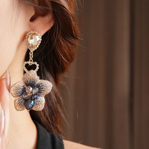 Détail de boucles d'oreilles vintage asymétriques avec fleurs en tissu bleu et cristaux