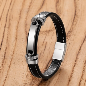 Braided black leather bracelet with silver metal plate and white stitching on wood surface