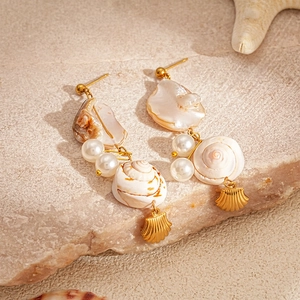 Detail of seashell and pearl long earrings on a natural stone with beach decorations