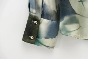 Détail des poignets en satin avec imprimé abstrait bleu et boutons dorés élégants