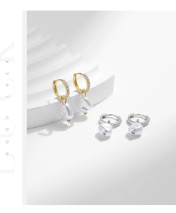 Macro detail of Baroque pearl drop earrings with micro-set zircons on gold and silver hoops