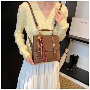 Detail of vintage brown crossbody bag with metal key charm and woven cord on model
