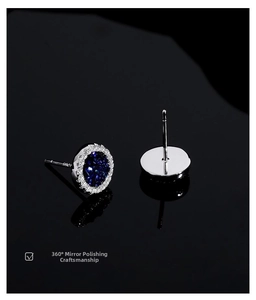 Macro detail of polished blue crystal stud earrings with white zircon halo on reflective surface