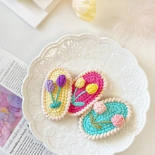 Close-up of handmade crochet flower hair clips in yellow, pink and blue wool knit