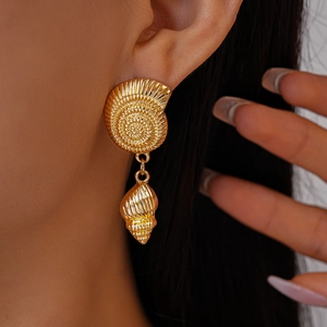 Macro shot of gold seashell earrings featuring textured nautilus shell and conch drops