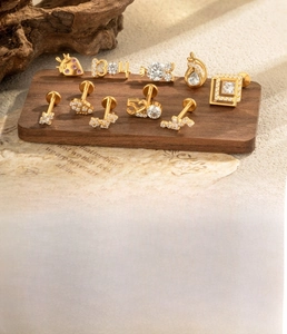 Detail of titanium labret studs with white zircon and geometric shapes on a display stand