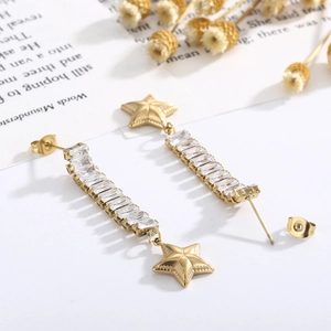 Close-up of gold star earrings with rectangular zircon tassels on decorative paper