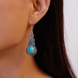 Close-up of vintage geometric leaf earrings with blue rhinestones and turquoise stone