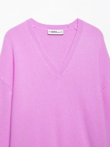 Detail view of the V-neckline and inner label on a soft pink knitted sweater