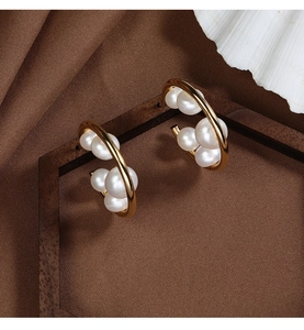 Close-up of golden hoop earrings with white pearls on elegant brown silk background