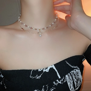 Close-up of double-layered pearl necklace with pink gemstone beads and crystal pendant