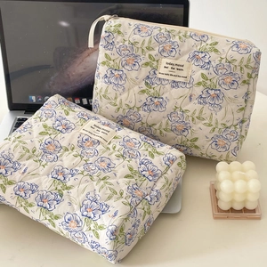 Detailed macro of the blue floral quilted cotton makeup bag featuring a fabric brand label