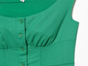 Detail view of green linen dress with square neckline, buttons and fabric texture