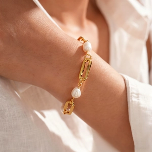 Detailed shot of 18k gold-plated oval link chain bracelet with irregular pearls on wrist