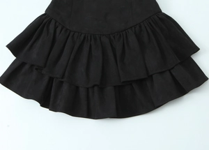 Détail d'une robe courte en daim noir avec ourlet à double épaisseur et détails plissés