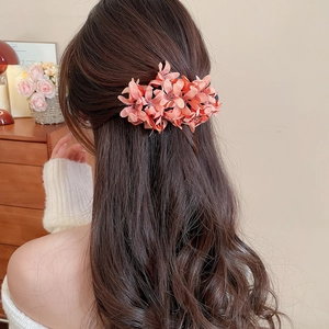 Detail of coral fabric floral hair clip worn on elegant hair in a cozy home setting