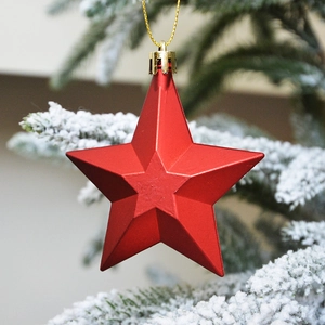 Red 3D star Christmas tree ornament with golden cord hanging on a snowy branch