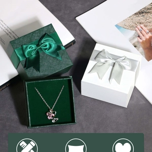 Detail view of butterfly pendant necklaces with ribbon gift boxes in green and white