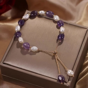 Detailed view of purple crystals and baroque pearls bracelet on a luxury gift box
