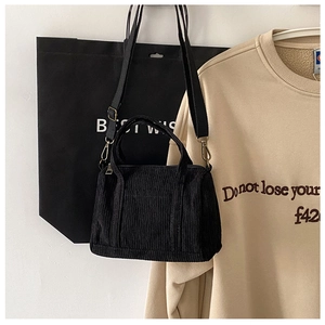 Detail view of black corduroy Boston bag with top handles and adjustable shoulder strap