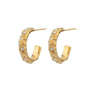 Detail of gold C-shaped earrings with molten lava texture and sparkling white zircons
